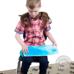 seated boy wearing a puppy hugs shoulder wrap while doing a fine motor activity
