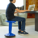 student on a wobble stool using a computer at a desk