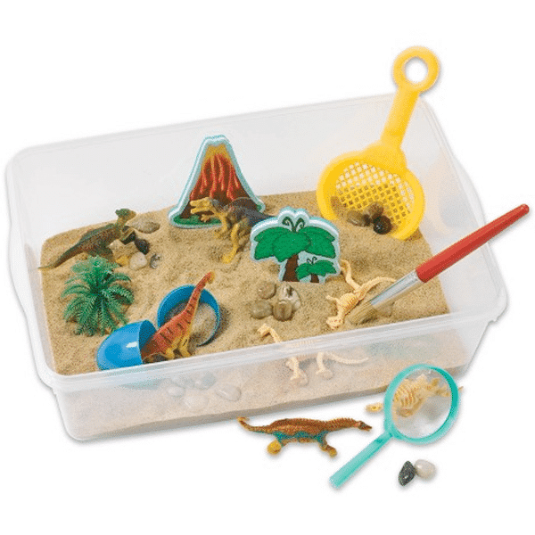Sensory bin with sand, dinosaurs and other manipulatives, a brush, a magnifying glass, and a sand sifter