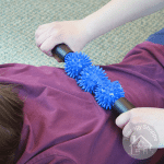 person rolling a spiky sensory rolling pin on a child's back