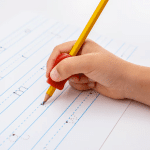a person's hand writing with a pencil using the pencil grip